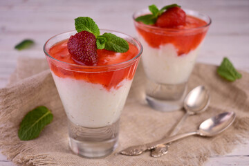 Rice pudding with strawberry jam in tall glasses on a white background.
