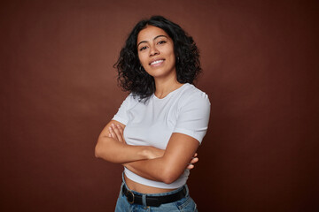 Young colombian curly hair woman isolated on brown background happy, smiling and cheerful.