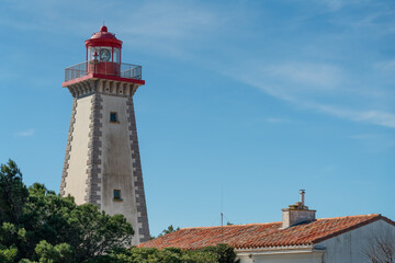 Fototapeta na wymiar Old white and red non-working lighthouse in the south of France. Lighthouse tower built from white and red bricks.