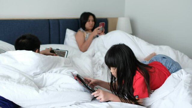 child playing tablet with mother on the bed
