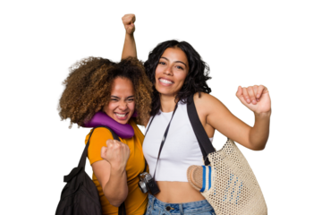 Two diverse friends on a beach vacation with vintage camera, beach bag, and travel pillow raising fist after a victory, winner concept.