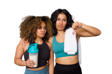 Two best friends are ready to go to the gym, one of them holds a protein shake, showing a dislike gesture, thumbs down. Disagreement concept.