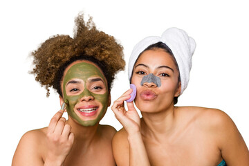 Two friends pamper themselves with facial treatments for a relaxing spa day at home, with laughter...