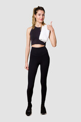 Fototapeta premium Full body of young woman in sportswear, fit and athletic, embodying a healthy and active lifestylesmiling and raising thumb up