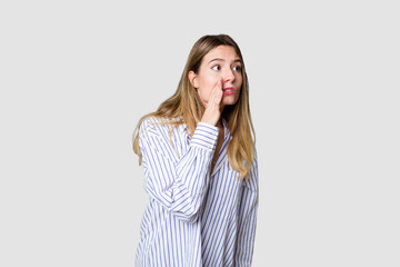 Young blonde posing for a portrait isolated, exuding natural beauty and radiance being shocked because of something she has seen.