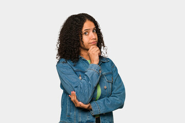 Young african american curly woman isolated suspicious, uncertain, examining you.
