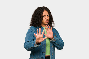 Young african american curly woman isolated rejecting someone showing a gesture of disgust.
