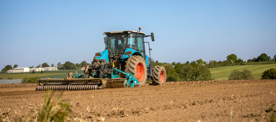 Travail de la terre par un tracteur en pleine nature au milieu des champs.