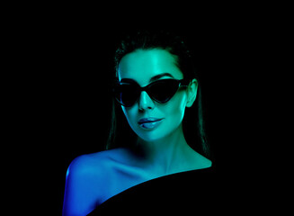 Beautiful woman wearing sunglasses in neon lights against black background