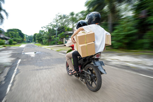 Rear view of Asian Muslim family carrying a box on a motorcycle going home