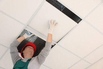 Suspended ceiling installation. Builder working with PVC tile, low angle view - obrazy, fototapety, plakaty