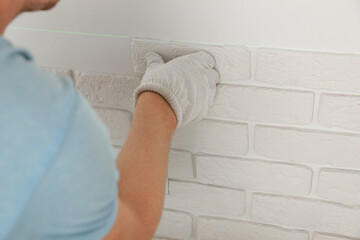 Obraz na płótnie Canvas Worker installing decorative wall tiles in room, closeup