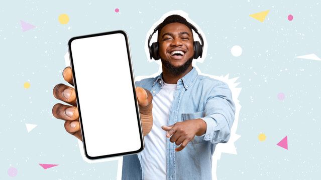 Happy black man using headphones, showing smartphone, mockup
