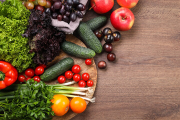 Different fresh ripe vegetables and fruits on wooden table, flat lay. Space for text