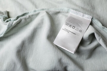 Clothing label on pale olive garment, closeup. Space for text