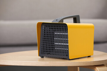 Modern electric fan heater on coffee table in room. Space for text
