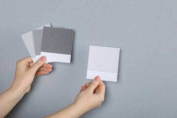 Woman with color sample cards choosing paint shade near grey wall, closeup. Interior design - obrazy, fototapety, plakaty