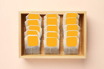 Many tea bags in wooden box on color background, flat lay