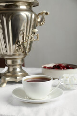 Vintage samovar, cup of hot drink and snacks served on table. Traditional Russian tea ceremony