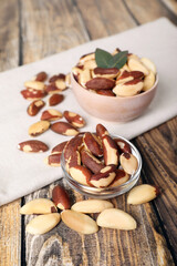 Bowls with delicious Brazil nuts on wooden table