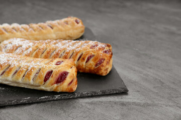 Fresh tasty puff pastry with sugar powder on grey table, closeup. Space for text
