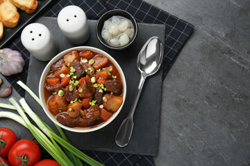Delicious beef stew with carrots, green onions and ingredients on grey table, flat lay. Space for text