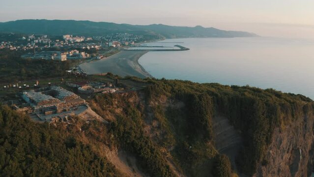 Drone view of the lighthouse in the trees, the white lighthouse building built on the edge of the cliff