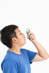 Asian boy using blue asthma inhaler for relief asthma attack. Medicinal products are used to...