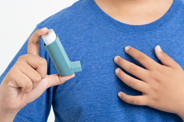 Asian boy using blue asthma inhaler for relief asthma attack. Medicinal products are used to prevent and treat asthma attacks and shortness of breath causing asthma or COPD, health care concept, - obrazy, fototapety, plakaty
