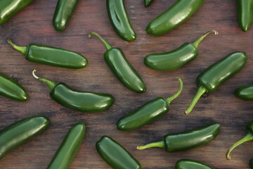 Many fresh green jalapeno peppers on wooden table, flat lay