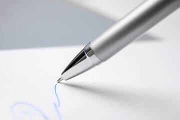 Signing on sheet of white paper with pen, closeup