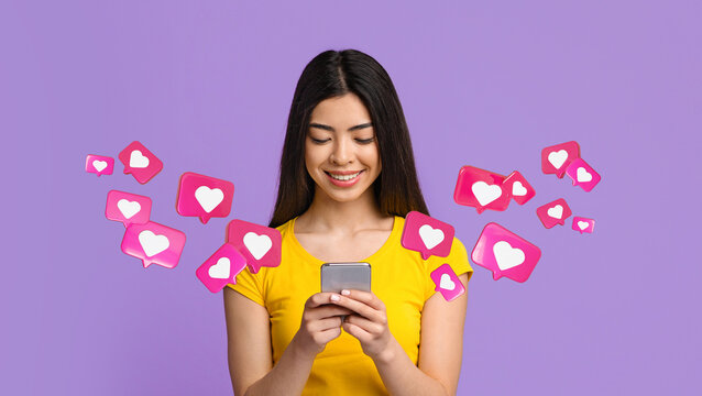 Cheerful teen japanese woman student has romantic chat with hearts on phone, enjoys message, texting