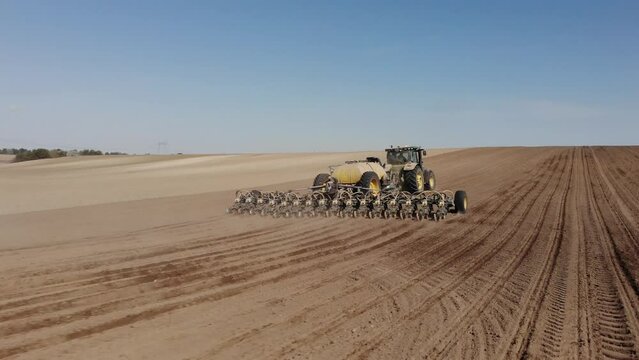 Green tractor planting sunflower on the sandy field in Ukraine 4K