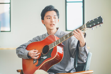 自宅でアコースティックギターを弾く若い男性