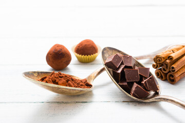 chocolate truffles, cocoa powder, broken dark chocolate on white wooden