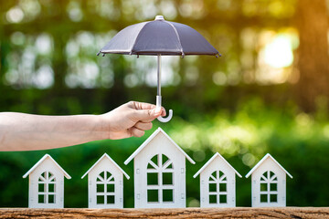 Woman hand hold open the black umbrella for protect the home model put on the wood in the public...