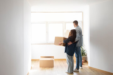 Fototapeta na wymiar Real Estate. Couple With Cardboard Boxes In Hands Standing In New Home