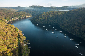 Scenic early morning aerial view of mist rising over Berowra Waters, NSW, Australia.