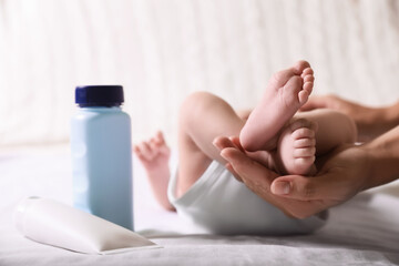 Mother holding baby`s legs on bed, closeup