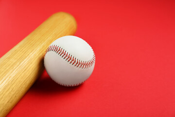 Wooden baseball bat and ball on red background, closeup. Space for text