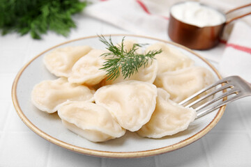 Cooked dumplings (varenyky) with tasty filling and dill on white table, closeup