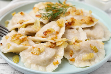 Cooked dumplings (varenyky) with tasty filling and fried onions on plate, closeup