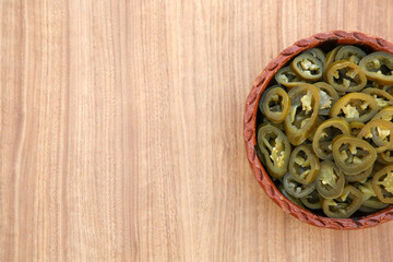 Pickled green jalapeno peppers on wooden table, top view. Space for text
