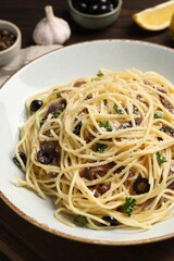 Delicious pasta with anchovies, olives and parmesan cheese on wooden table, closeup