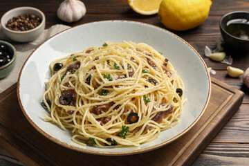 Delicious pasta with anchovies, olives and parmesan cheese served on wooden table