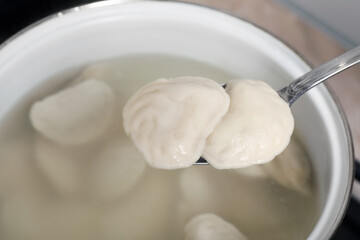 Fototapeta na wymiar Spoon with tasty dumplings (varenyky) over pot, closeup