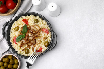 Tasty couscous with mushrooms, olives and tomatoes on grey table, flat lay. Space for text