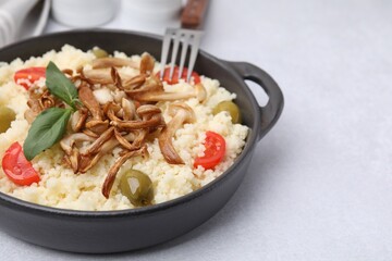 Tasty couscous with mushrooms, olives and tomatoes on grey table, closeup. Space for text