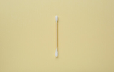 One wooden cotton bud on beige background, top view