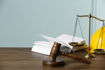 Labour, construction and land law concepts. Judge gavel, scales of justice, open book with protective helmet on wooden table, space for text